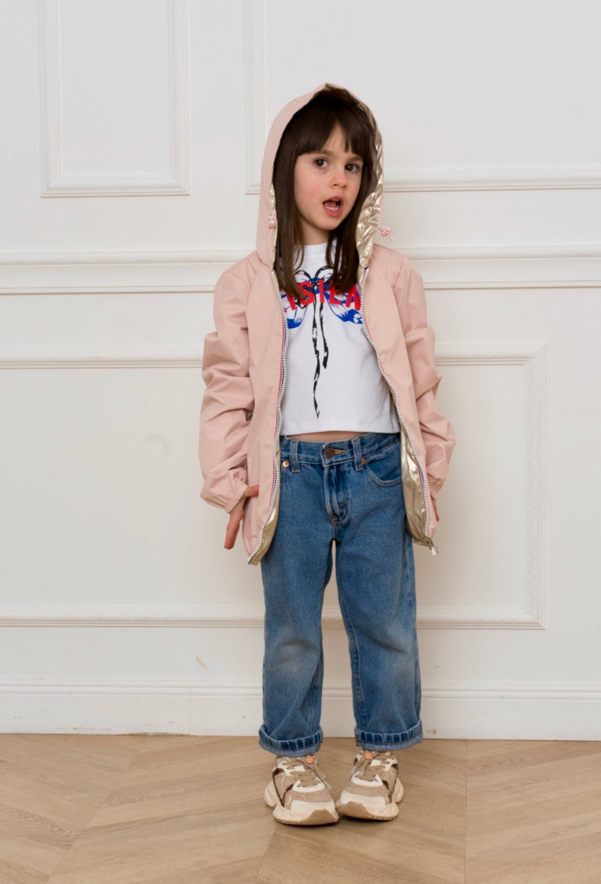 Jeune fille portant l'Imperméable réversible léger GARANCE KIDS LAURA JO, coupe droite, capuche avec cordon, deux poches zippées. Modèle mixte.